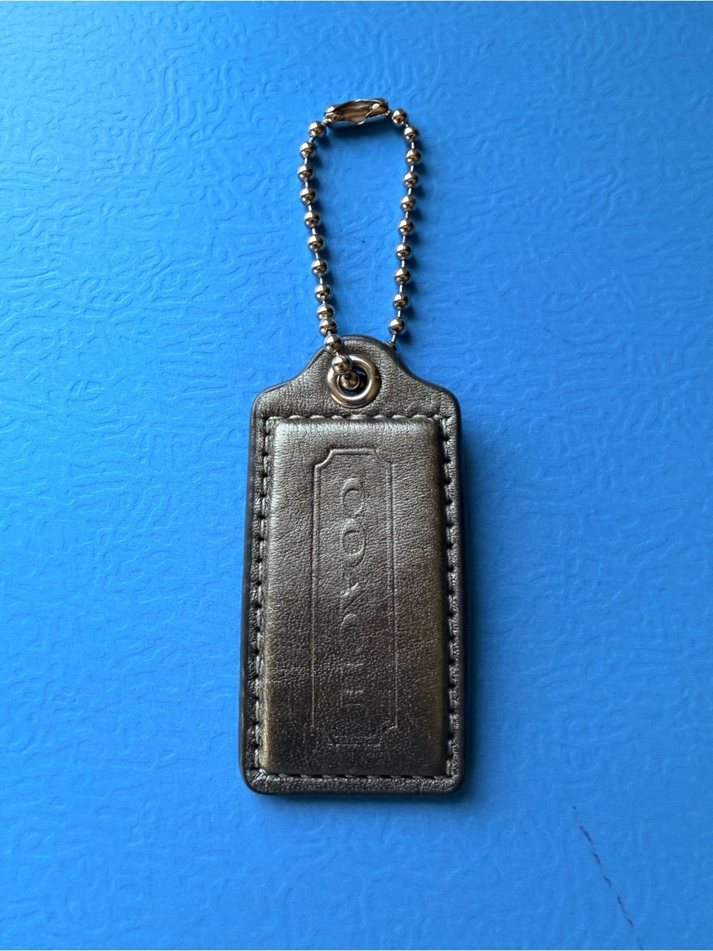 Coach hangtag, metallic pewter color, one sided logo